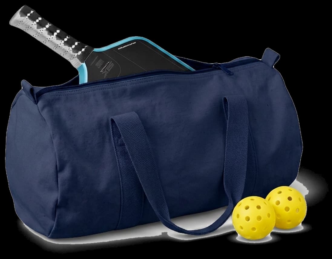 A navy canvas gym duffel with a pickleball paddle tucked into the zip and two balls beside it