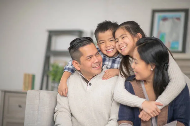 A family of four embracing at home, smiling together